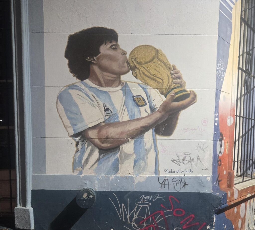murale di Diego Armando Maradona con la maglia dell'argentina che bacia la coppa del mondo